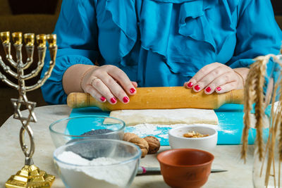 Women's hands roll out dough gomentash biscuits with poppy seeds, traditional for the jewish holiday