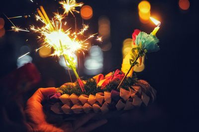 Close-up of lit sparklers on food at night