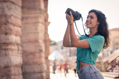 Smiling young woman photographing in city