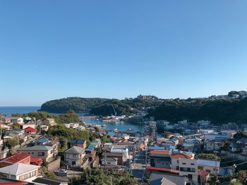 High angle view of townscape by sea against clear sky