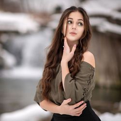 Portrait of young woman looking away while standing outdoors