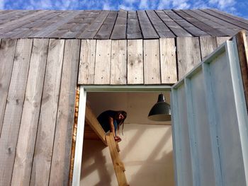 Young woman sitting on ladder in barn seen through doorway