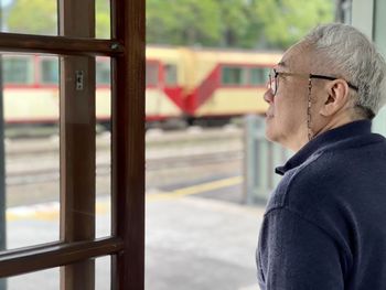 Side view of young man looking through window