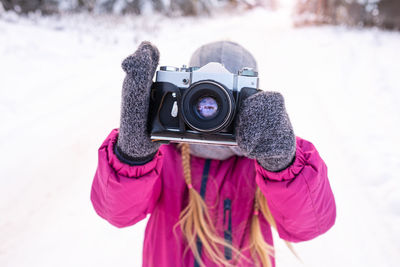 Close-up of slr film camera in raised hands of girl on winter walk. child taking a photo. 