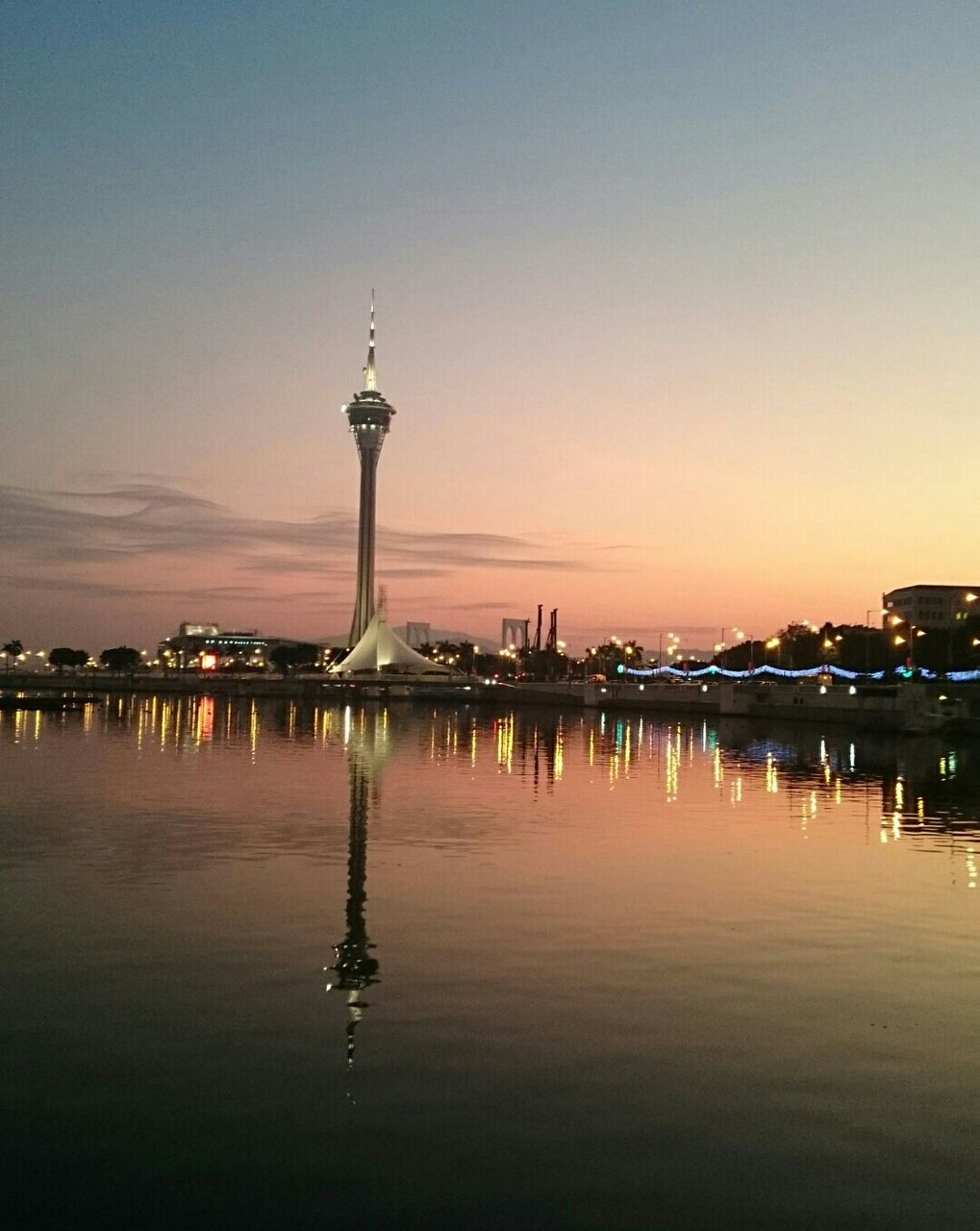 sunset, water, reflection, illuminated, built structure, architecture, building exterior, waterfront, communications tower, tower, sky, dusk, silhouette, city, tall - high, travel destinations, sea, no people, scenics, travel