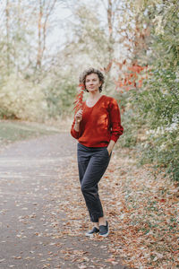 Full length portrait of young woman standing on tree