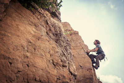 Low angle view of man on rock against sky