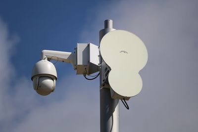 Low angle view of security camera on pole against sky