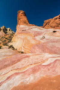 Colorful rock formations on landscape against clear blue sky in valleyof fire, nevada.