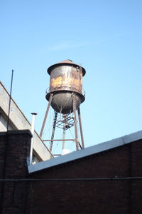 Low angle view of water tower on building against clear sky