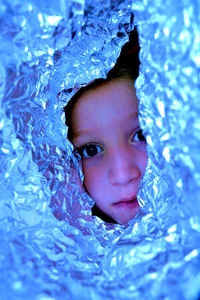 Portrait of girl looking through foil paper