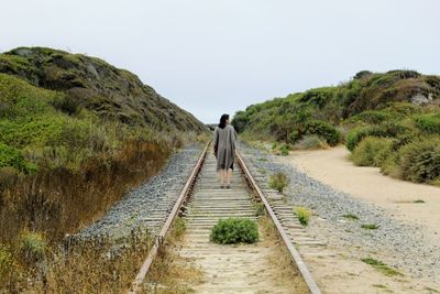 Rear view of man walking on walkway against sky