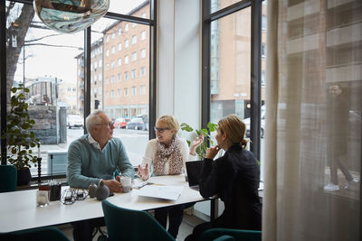 Retired couple talking while sitting with real estate agent in office