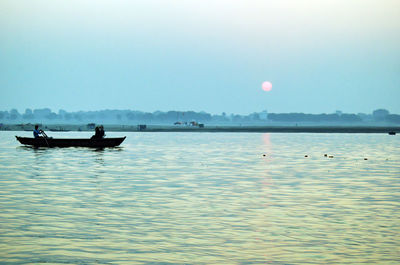 Silhouette people in lake against sky