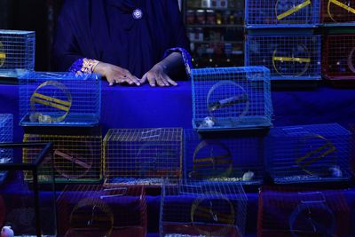 Midsection of woman selling birdcage at market stall