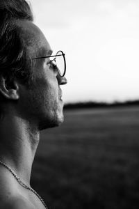 Close-up of young man looking away against sky