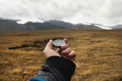 A man's hand of a traveler holds a magnetic compass against the background of a mountain landscape 