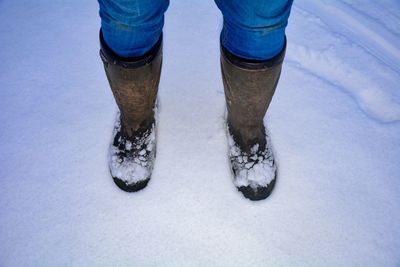 Low section of person standing on snow covered field