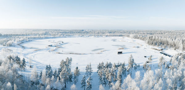 Aerial view of snow covered forest around beautiful lake.