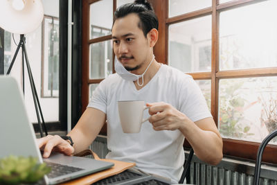 Young man using mobile phone while sitting on table