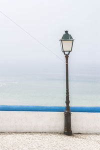 Street light by sea against sky