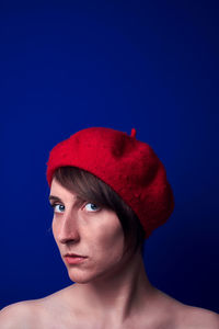 Close-up portrait of serious young woman looking away against blue background