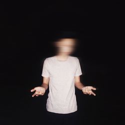 Man with blurry face standing against black background