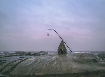 Windmill on rock against sky during winter