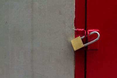 Textured of old dark cement wall and brass pad lock with strong gate red slide door and copy space.