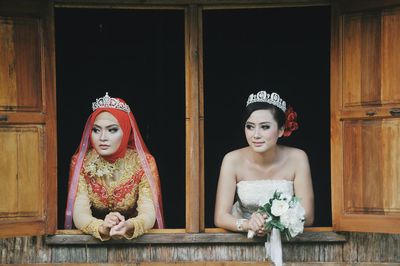 Brides wearing wedding dress while looking through windows