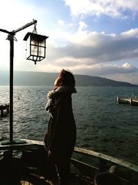 Woman standing at sea shore against sky