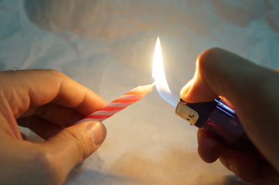 Human hand burning a candle with a lighter