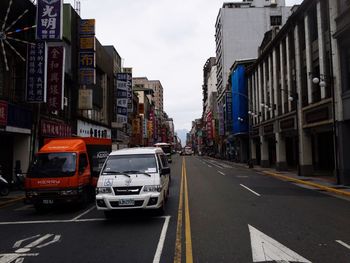 Cars on road in city against sky