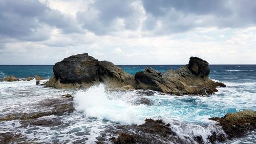 Scenic view of rocks in sea against sky