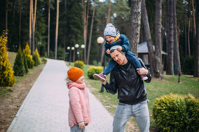 Father and two children walk in nature in autumn, spend time together, have fun.