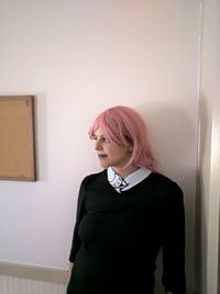 Woman looking away while standing against wall at home