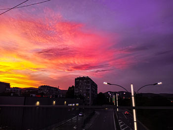 City street and buildings against sky during sunset