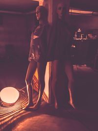 Young couple standing on table against illuminated light at night