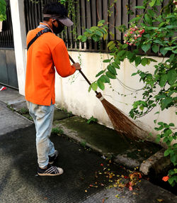 Man standing on footpath by potted plants