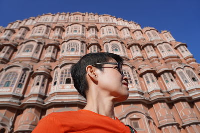 Low angle portrait of young man wearing sunglasses against sky