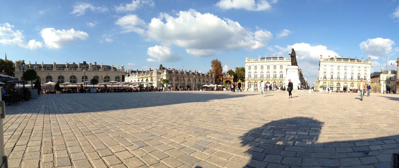 building exterior, architecture, built structure, sky, city, cobblestone, cloud - sky, incidental people, cloud, men, large group of people, person, sunlight, shadow, town square, lifestyles, city life, walking, leisure activity