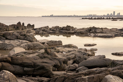 Rocks on beach against sky during sunset