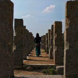 Rear view of person walking by stones