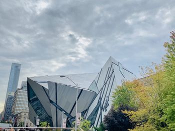 Low angle view of modern buildings against cloudy sky