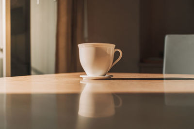 Hot cup of drink on the table in sun light of calm morning.