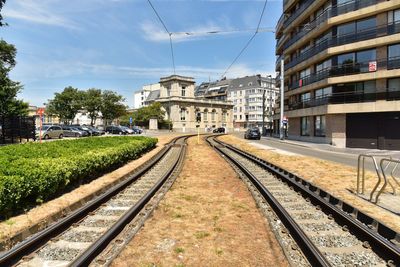 Railroad tracks amidst buildings in city against sky