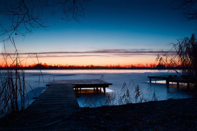 Pier on lake against sky during sunset