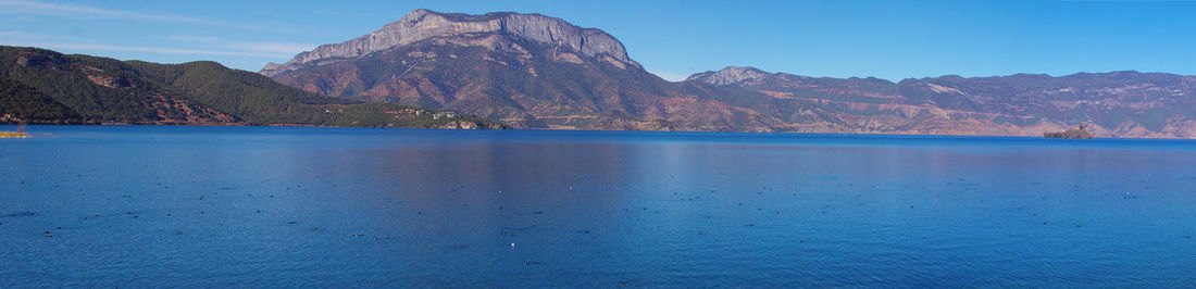 Scenic view of sea and mountains against blue sky