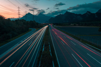 Light trails on road against sky at dusk