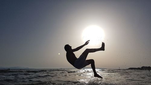 Silhouette person on beach against sky during sunset